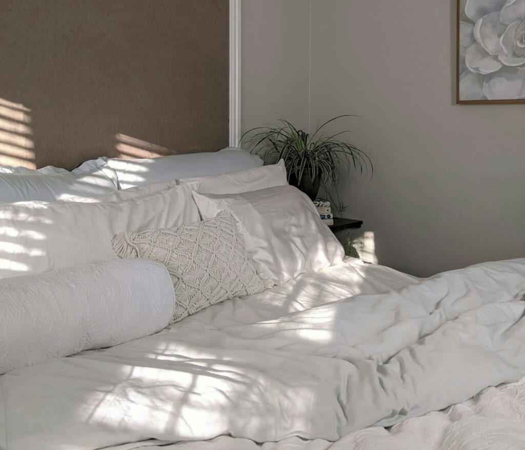 Bright bedroom with layered bedding, bedside lamps, woven storage baskets, and neatly arranged furniture