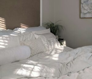 Bright bedroom with layered bedding, bedside lamps, woven storage baskets, and neatly arranged furniture