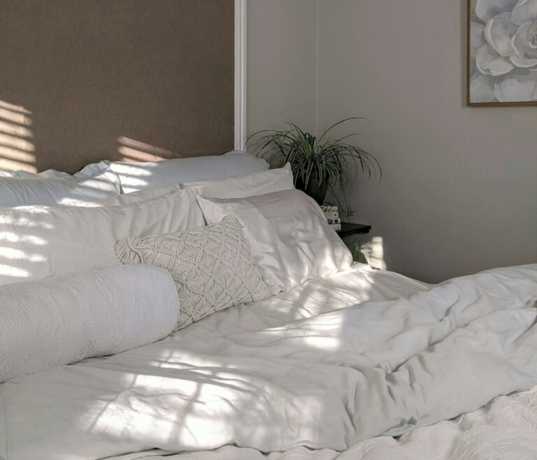 Bright bedroom with layered bedding, bedside lamps, woven storage baskets, and neatly arranged furniture